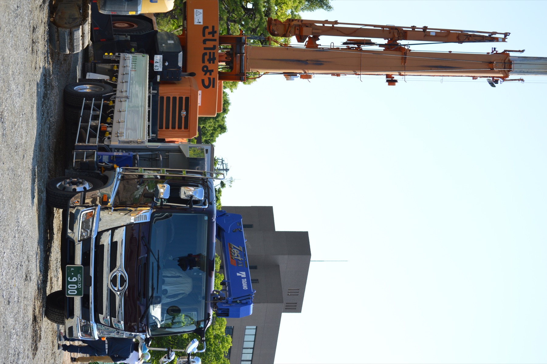 重量物運搬に対応する赤いクレーン付きユニック車